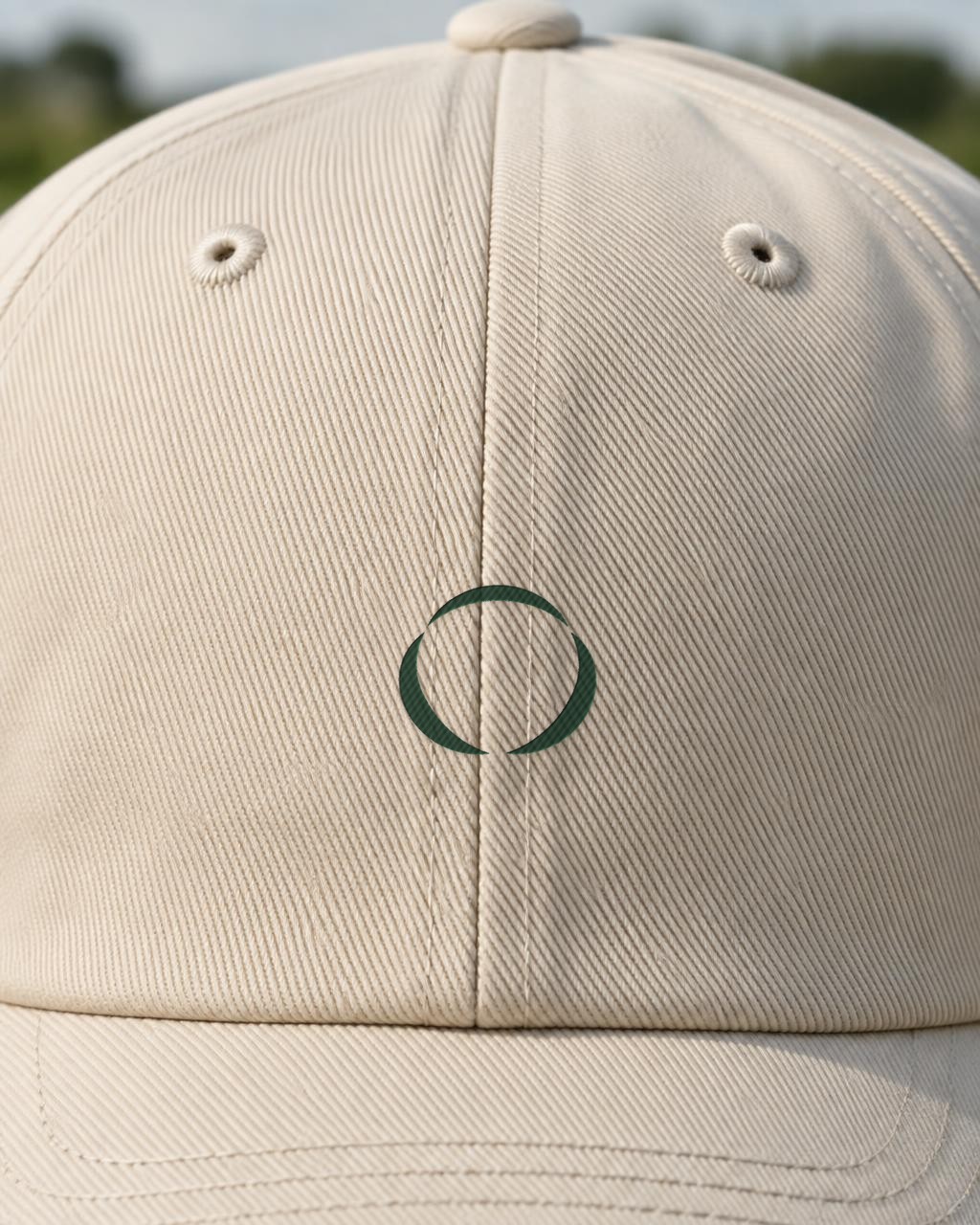 Close-up of the RTP symbol embroidered in deep green on a cream twill cap